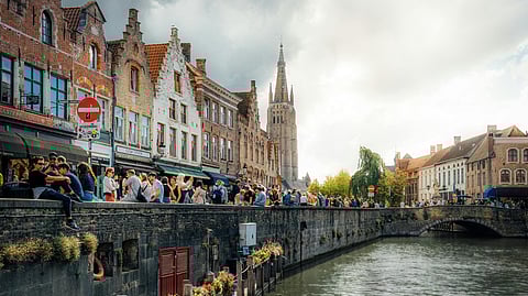People sitting by a canal in Bruges.