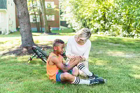 women caring for a child who is injured, and there is a scooter behind them.