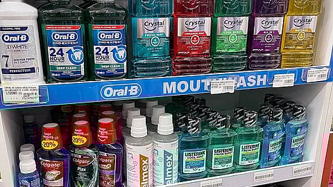 A group of mouthwashes lined up in a supermarket rack. 
