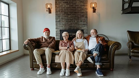 4 older people sitting together on couch.
