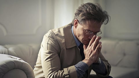 A man on the couch looking distressed.