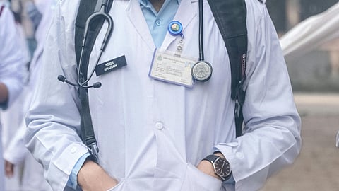 A student in white coat, with stethoscope around neck.