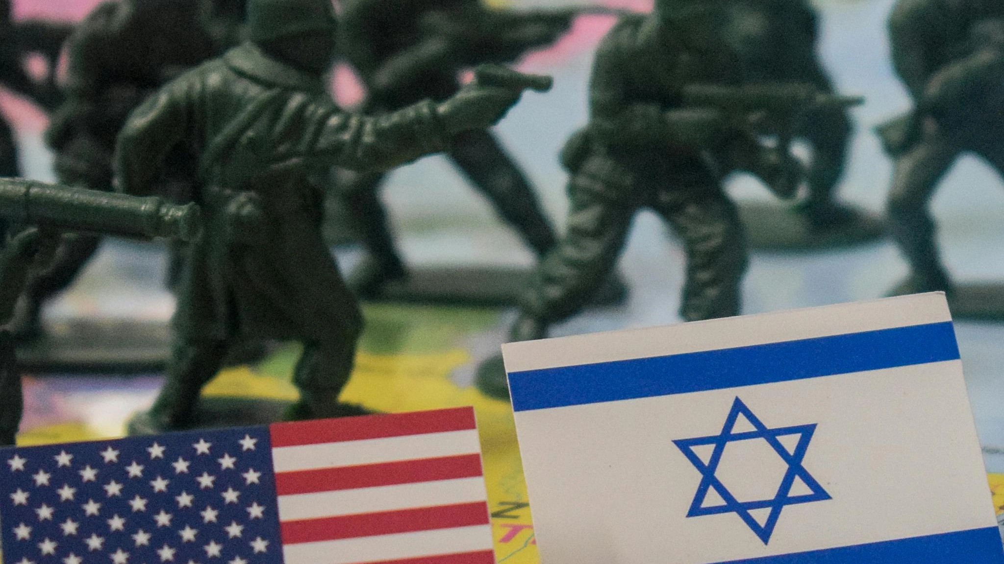 Toy soldiers on a world map with small American and Israeli flags in the foreground.