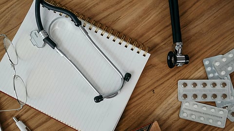 Stethoscope, notepad and medicines on desk.