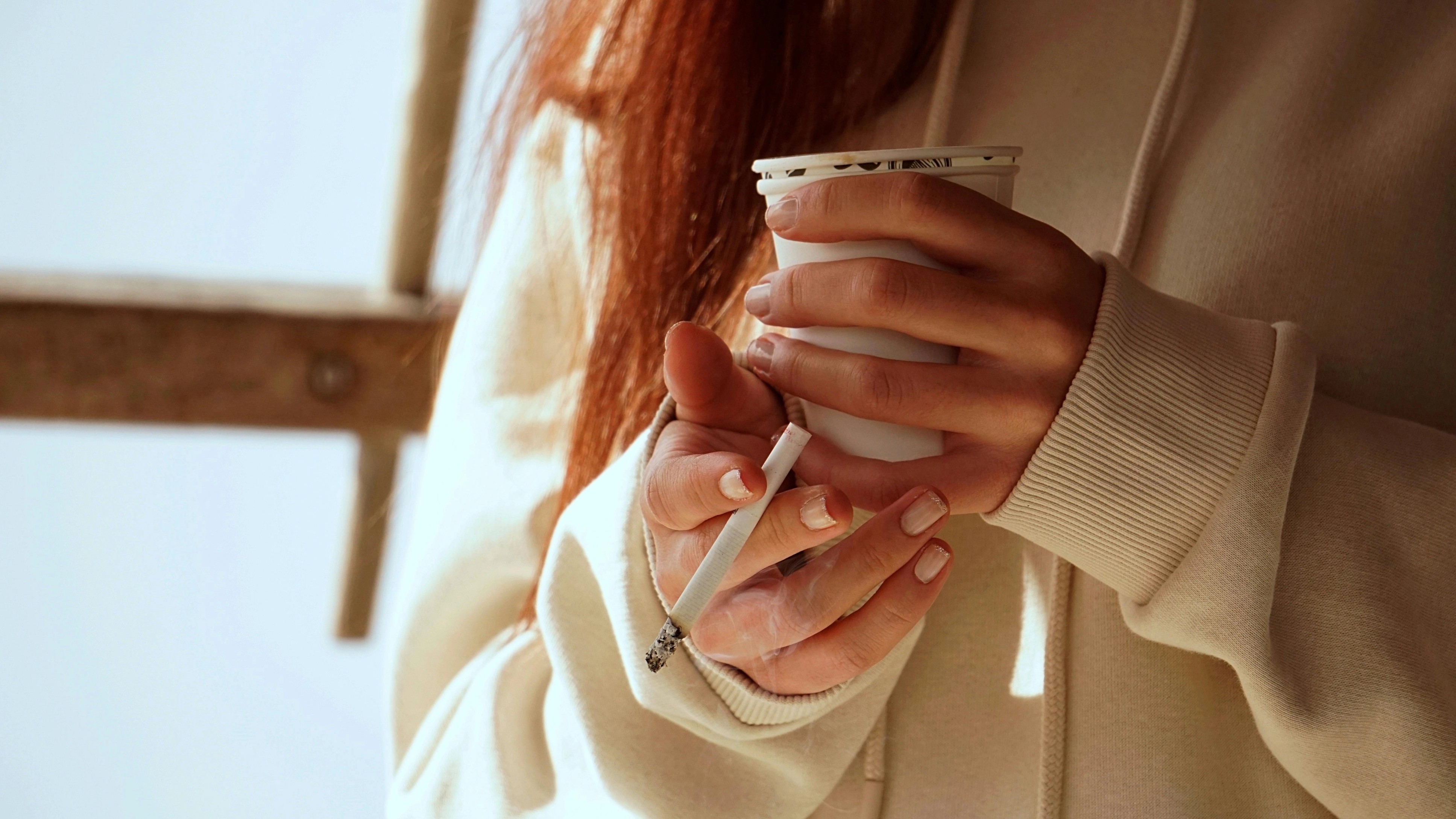 A woman holding cigarette and cup.