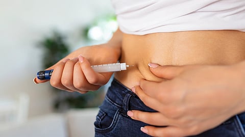 A person self-administers an injection into their abdomen using an insulin pen. 