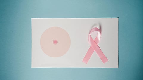 Pink ribbon symbolizing breast cancer awareness next to a stylized breast illustration on a white card.