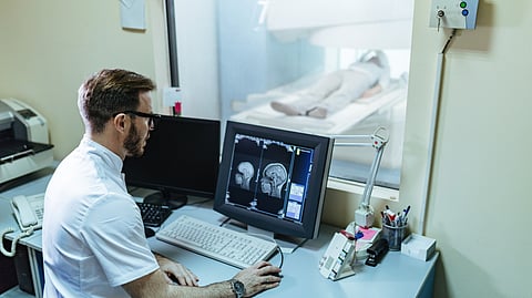 Male radiologist analyzing mri scan results of a patient on computer monitor