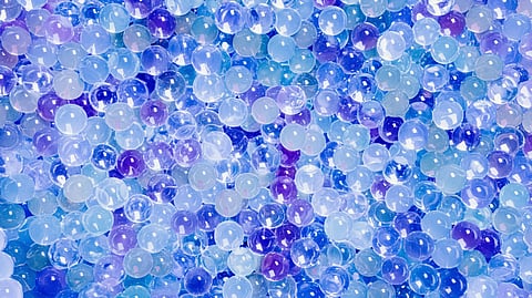 Vibrant close-up of transparent and colorful gel beads in shades of blue, purple, and light pink.