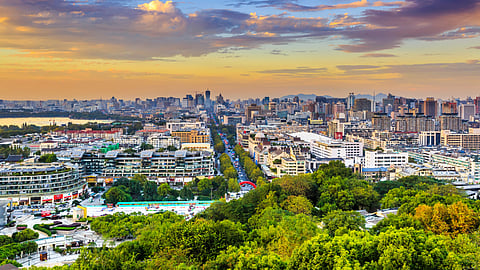 Buildings and greenery with a gradient sky.