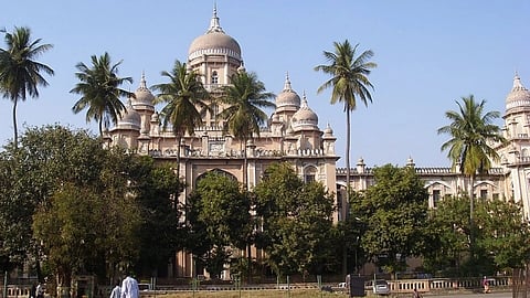 White buildings and coconut trees in front of Osmania Hospital.