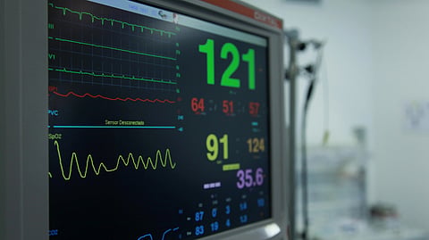 Hospital monitor showing heart rate and vital signs on a screen.