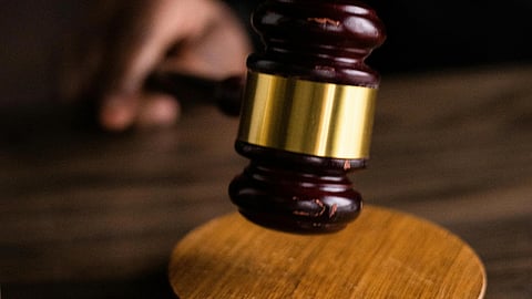 Dark courtroom scene with a hand holding a wooden gavel poised above a round sound block.