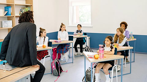 A teacher talks with students in a bright classroom.
