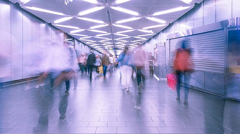 A busy subway corridor with people walking under bright lights.