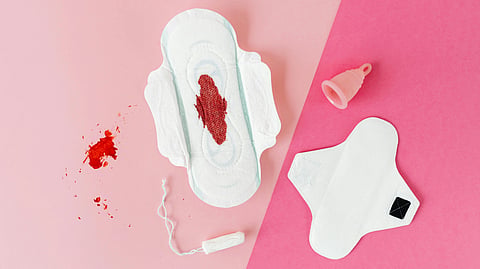 Menstrual products like pad, tampon, and cup shown on a pink background.