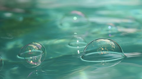 Translucent soap bubbles gracefully float on a turquoise water surface.