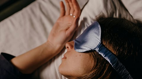 A woman sleeping with a blue sleeping mask,