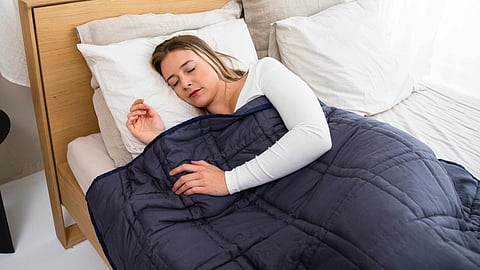 A woman sleeping with a navy blanket on.