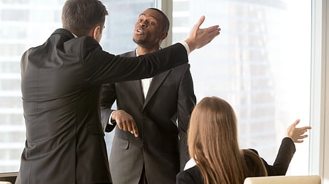 Three professionals in suits engaged in a heated discussion in an office. 