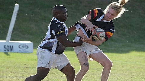 A rugby player tackles an opponent carrying the ball during a match.