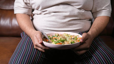 Person holding a bowl of vegetables and healthy food illustrating obesity, nutrition, and weight loss management.