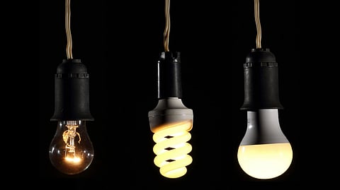Three hanging light bulbs against a black background.