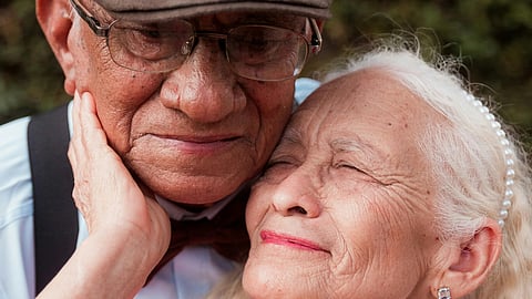 Close-up of an elderly couple embracing affectionately outdoors, symbolizing love and emotional intimacy in aging.