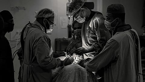 A surgical team performs an operation under bright operating room lights.