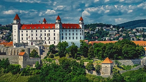 A red and white castle in between green lands.