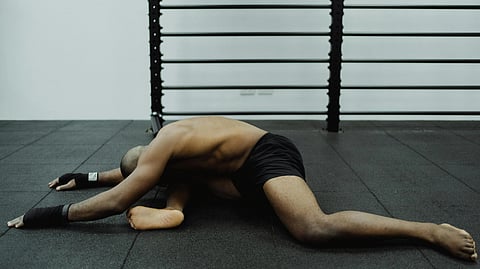 A man kneels on the gym floor, focused on his workout routine.