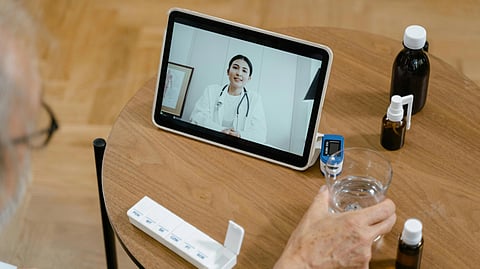 Elderly person participates in a telehealth session from home, viewing a doctor on a tablet.
