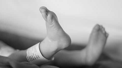 Close-up of newborn baby feet in a hospital setting representing the deaths of six infants at a Dhaka hospital under investigation.