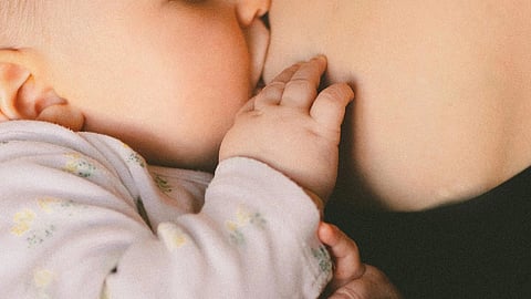 Mother breastfeeding her infant in an indoor setting, associated with themes of maternal and child health and nutrition.