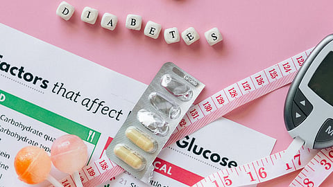 Diabetes supplies, medicine, and a glucose meter arranged on health documents.