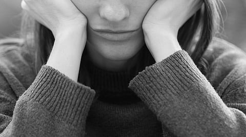 A girl holding her face in her hands.