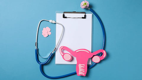 A stethoscope, clipboard, and pink uterus symbol on a blue background representing women’s health.