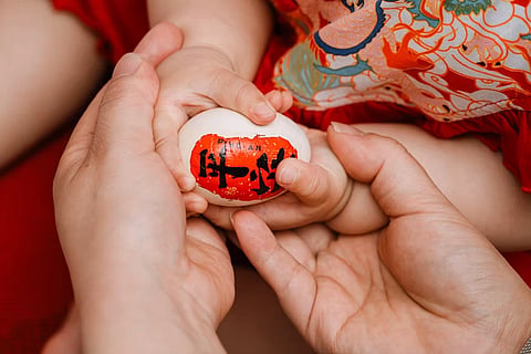 Parents holding a baby’s hands with a symbolic egg representing fertility, IVF, and egg donation treatment