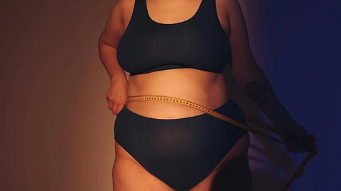 woman measuring their waist with a tape measure.