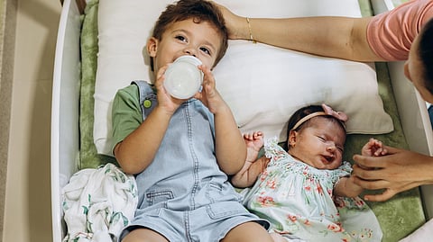 A woman and two children are comfortably lying together in a bed.