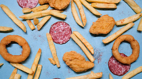 A blue background featuring an assortment of fried foods, including crispy onion rings.