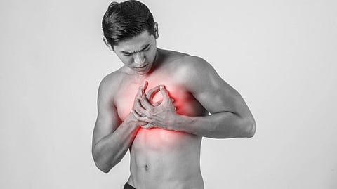 A shirtless man clutching his chest in pain, with a red glow highlighting the chest area.