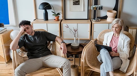 A man and woman sitting on chairs in a cozy living room, engaged in conversation.