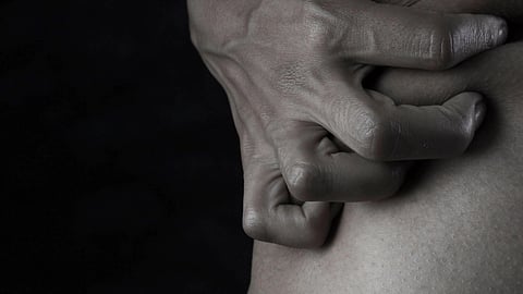 A man stands with his hands on his stomach.