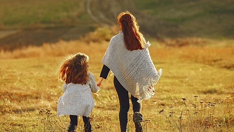 Mother with little daughter playing in a autumn field