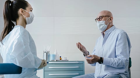 A doctor speaks with an elderly patient during a clinic visit.