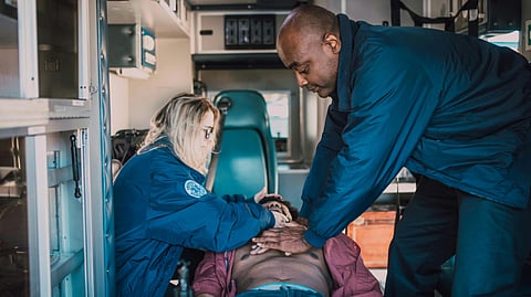 Emergency responders perform CPR on a patient in an ambulance during a medical emergency.