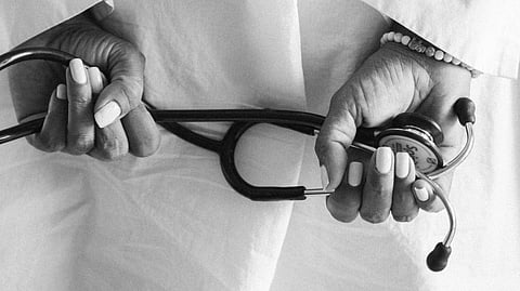 Doctor holding a stethoscope behind his back.