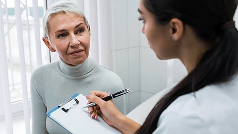 A healthcare professional listens to an older woman during a consultation.