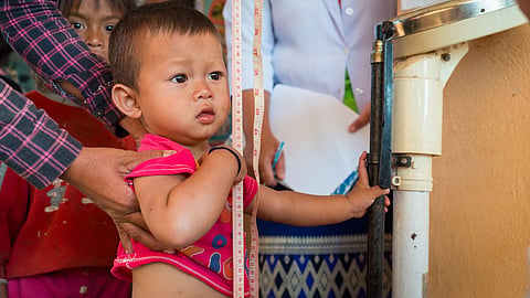 A child’s height is being measured while an adult offers support.